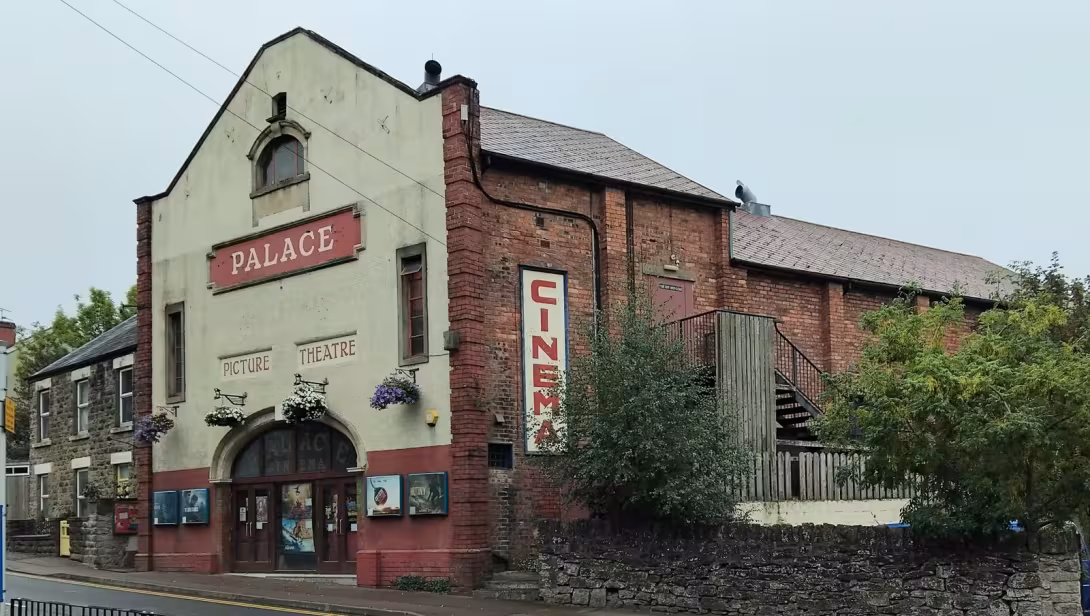 The Palace Picture Theatre in Belle Vue Road, Cinderford: a cream-and-red frontage with hanging baskets and a tall CINEMA sign.